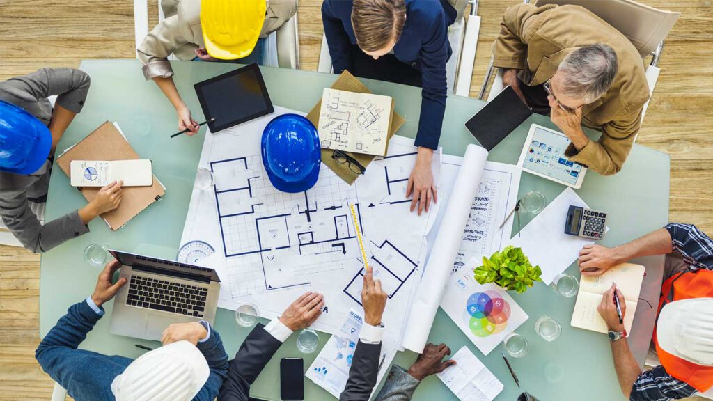 Ein Team sitzt an einem Tisch und arbeitet einen Plan aus.
